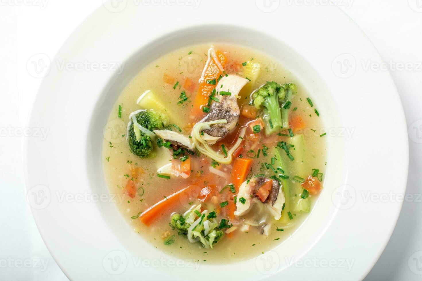 Light fish soup with vegetables and broccoli in white plate. photo