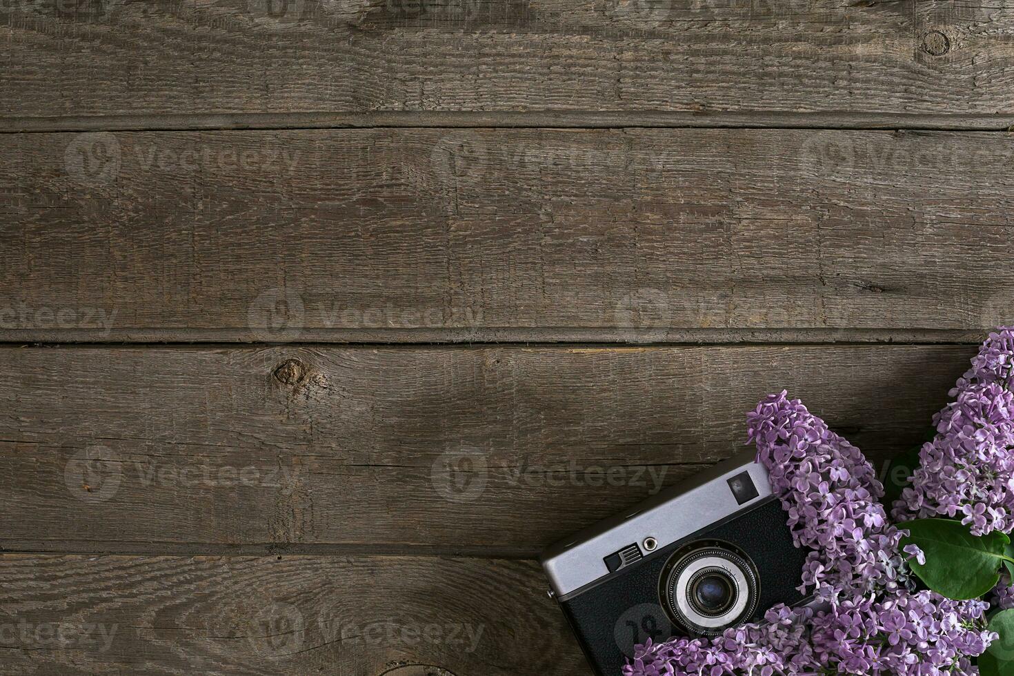 Lilac blossom on rustic wooden background with empty space for greeting message. Camera old. Top view photo