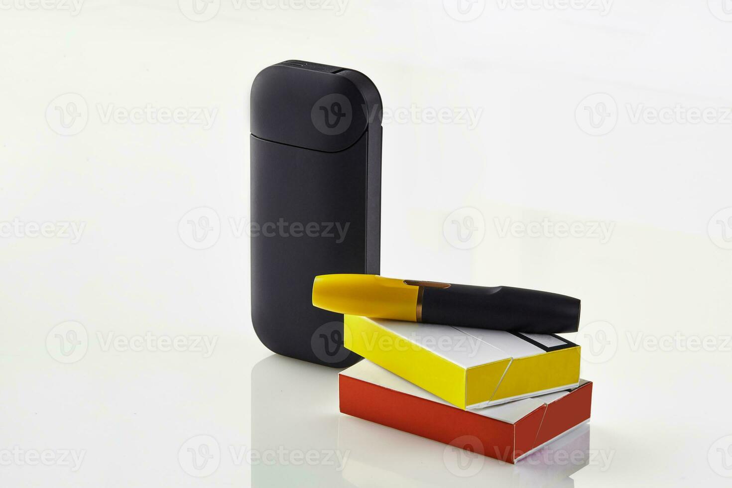 New generation black electronic cigarette is on red and yellow matchboxes, battery, isolated on white. Heating tobacco system. Advertising, close up photo