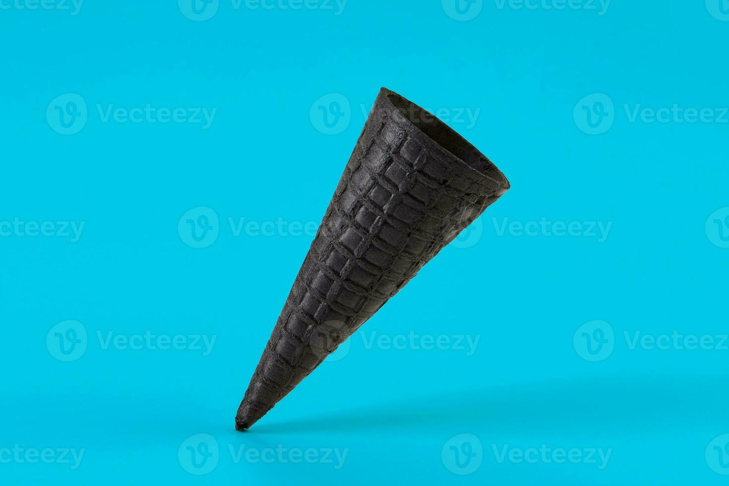 Empty, tasty black wafer cone for ice cream on blue background. Concept of food, treats. Mockup, template for your advertising and design. Close up photo