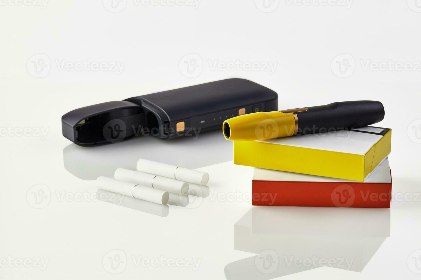 Black electronic cigarette is on packs with red and yellow sides, open battery, three heatsticks isolated on white. Heating tobacco system. Close up photo
