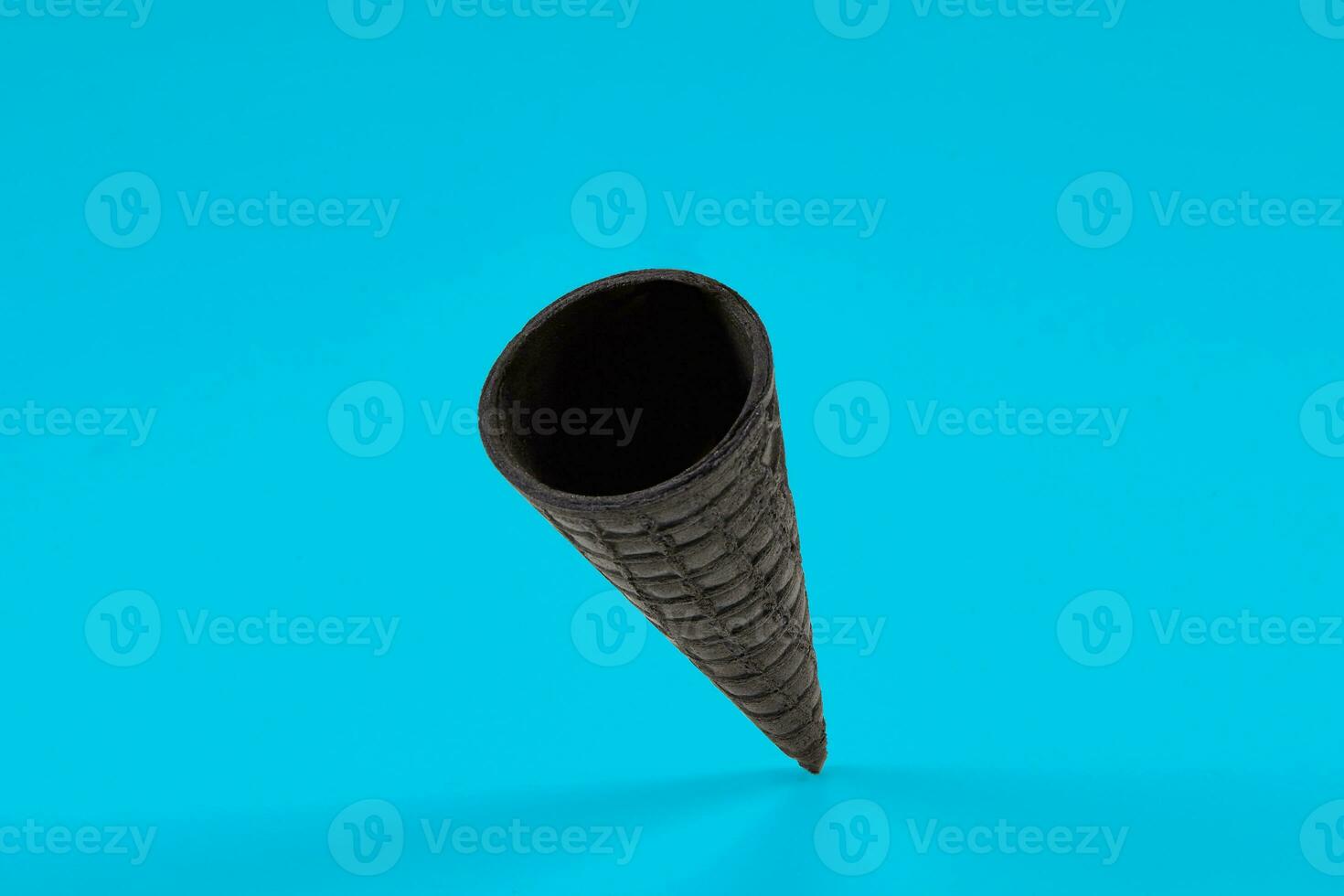 Empty, crispy black wafer cone for ice cream on blue background. Concept of food, treats. Mockup, template for your advertising and design. Close up photo