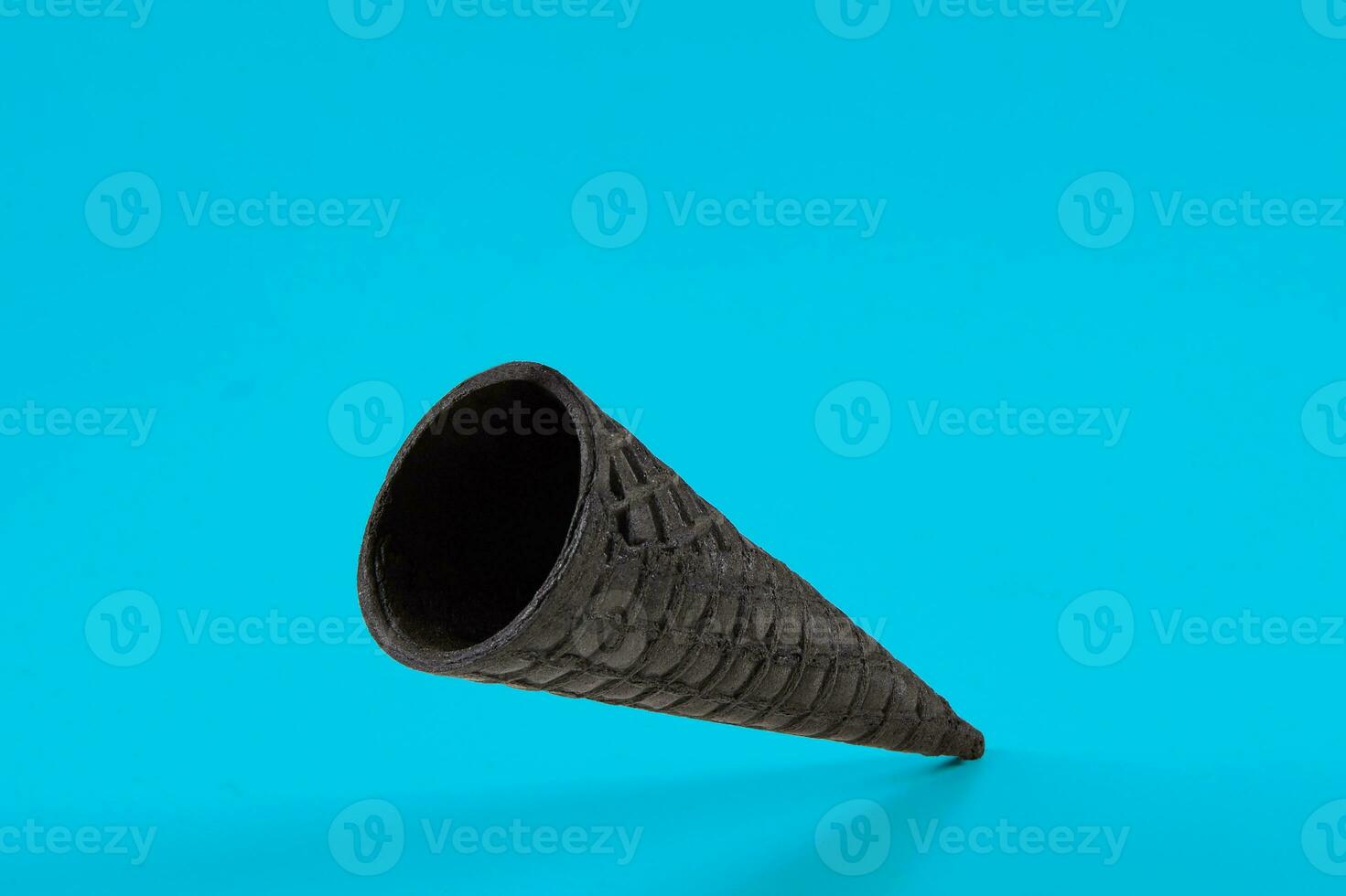 Empty, delicious black wafer cone for ice cream on blue background. Concept of food, treats. Mockup, template for your advertising or design. Close up photo