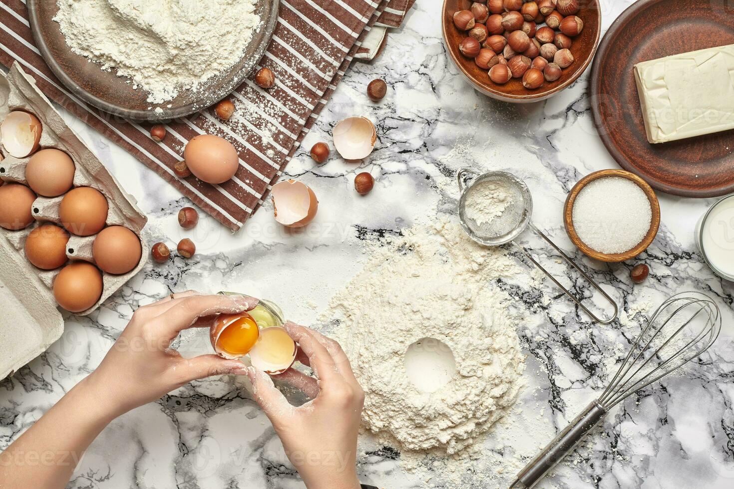 Close-up shot. Top view of a baker cook place, hands are working with a raw dough on the marble table background. photo