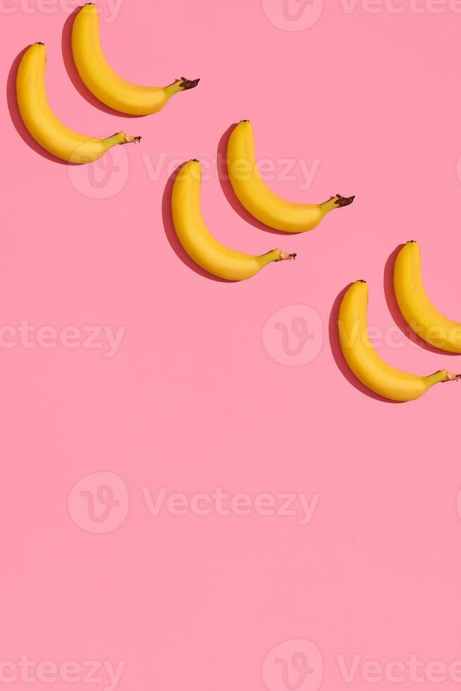 Pattern composition of a pair of bananas lying next to a pink background , top view photo