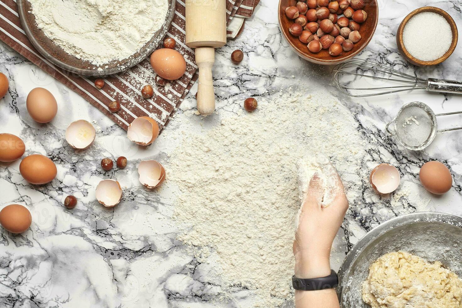 Close-up shot. Top view of a baker cook place, hands are working with a raw dough on the marble table background. photo