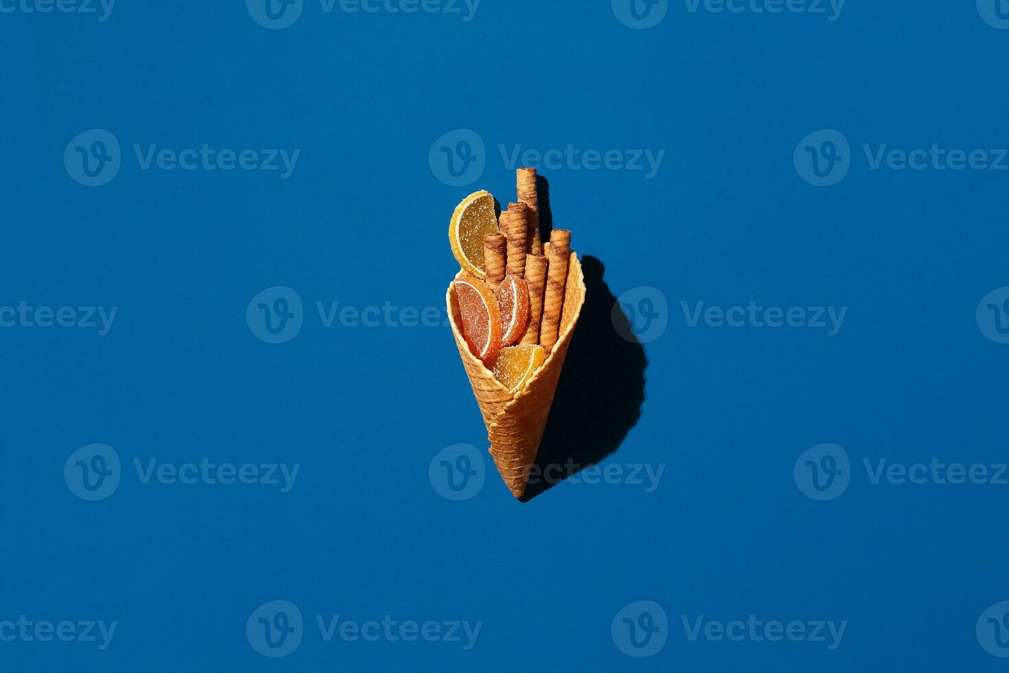 Wafer rolls and marmalade from waffle cone on blue background photo