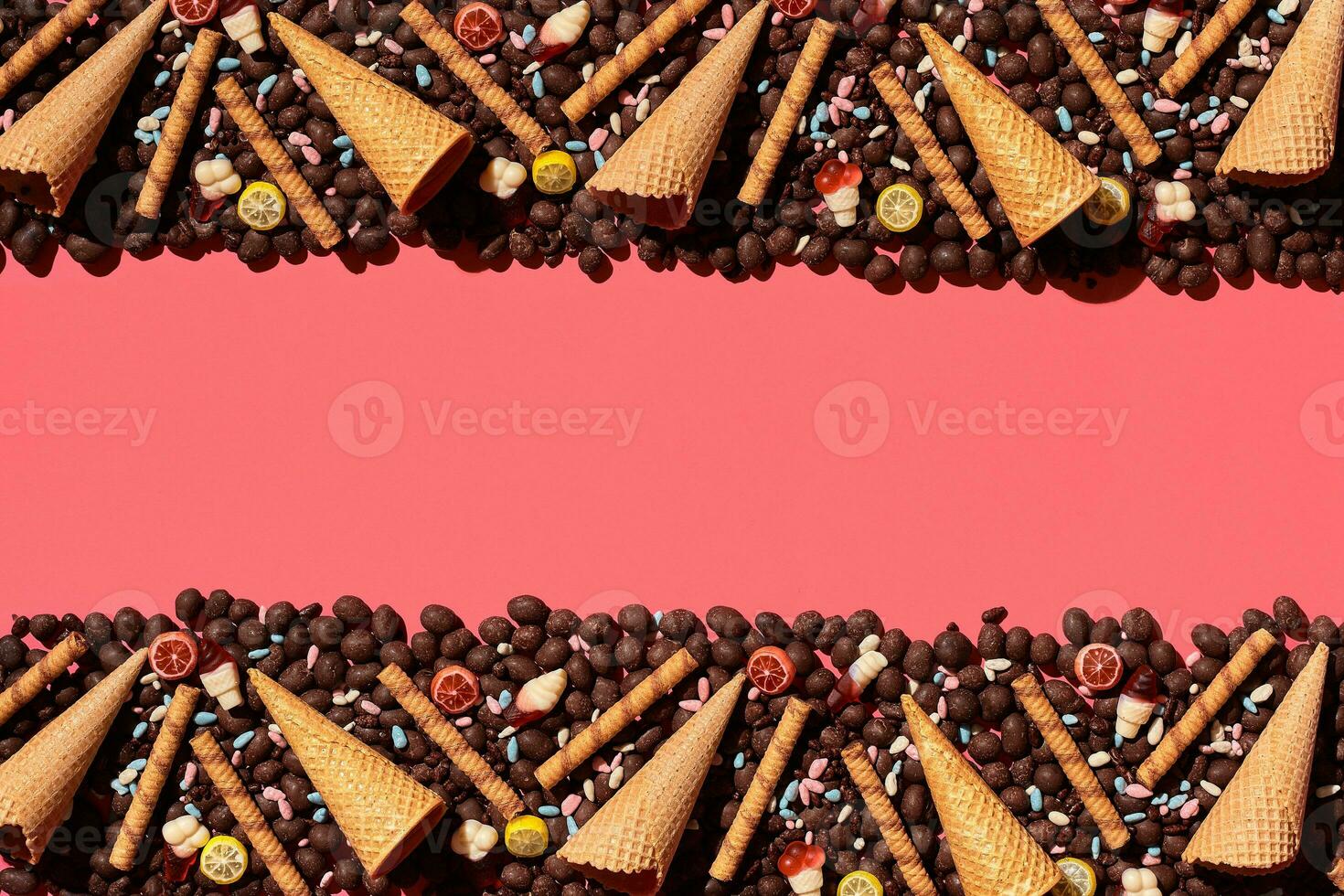 Chocolate dragee and waffle cones placed in fascinating order on coral background, view from above photo