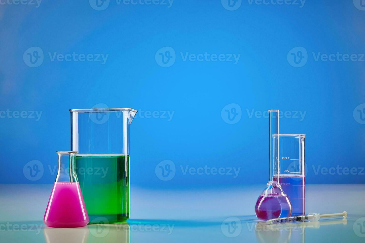 Medical flasks and two beakers, colorful chemical reagents for tests, blue background. Laboratory research of Coronavirus. Worldwide pandemic COVID-19 photo