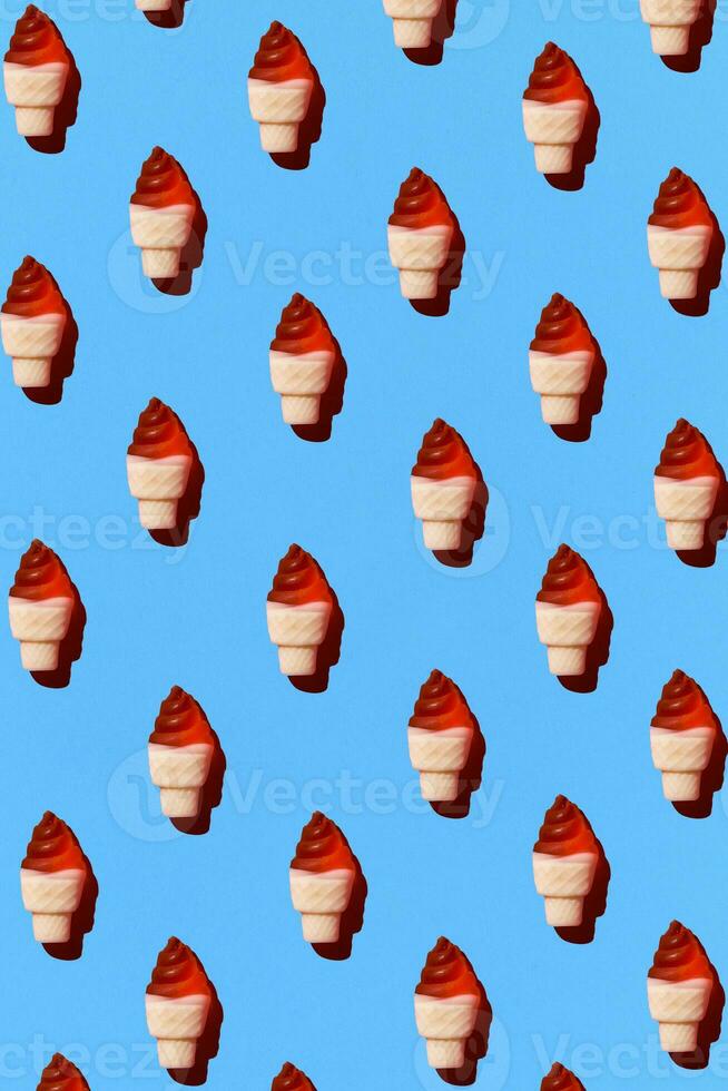 Pattern made of colorful jelly ice cream cones on blue background. Flat lay. Minimal concept photo