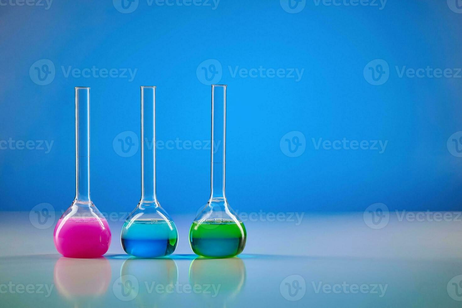 Three medical flasks with colorful chemical reagents for tests, blue background. Laboratory research of Coronavirus. Pandemic COVID-19. Close up photo