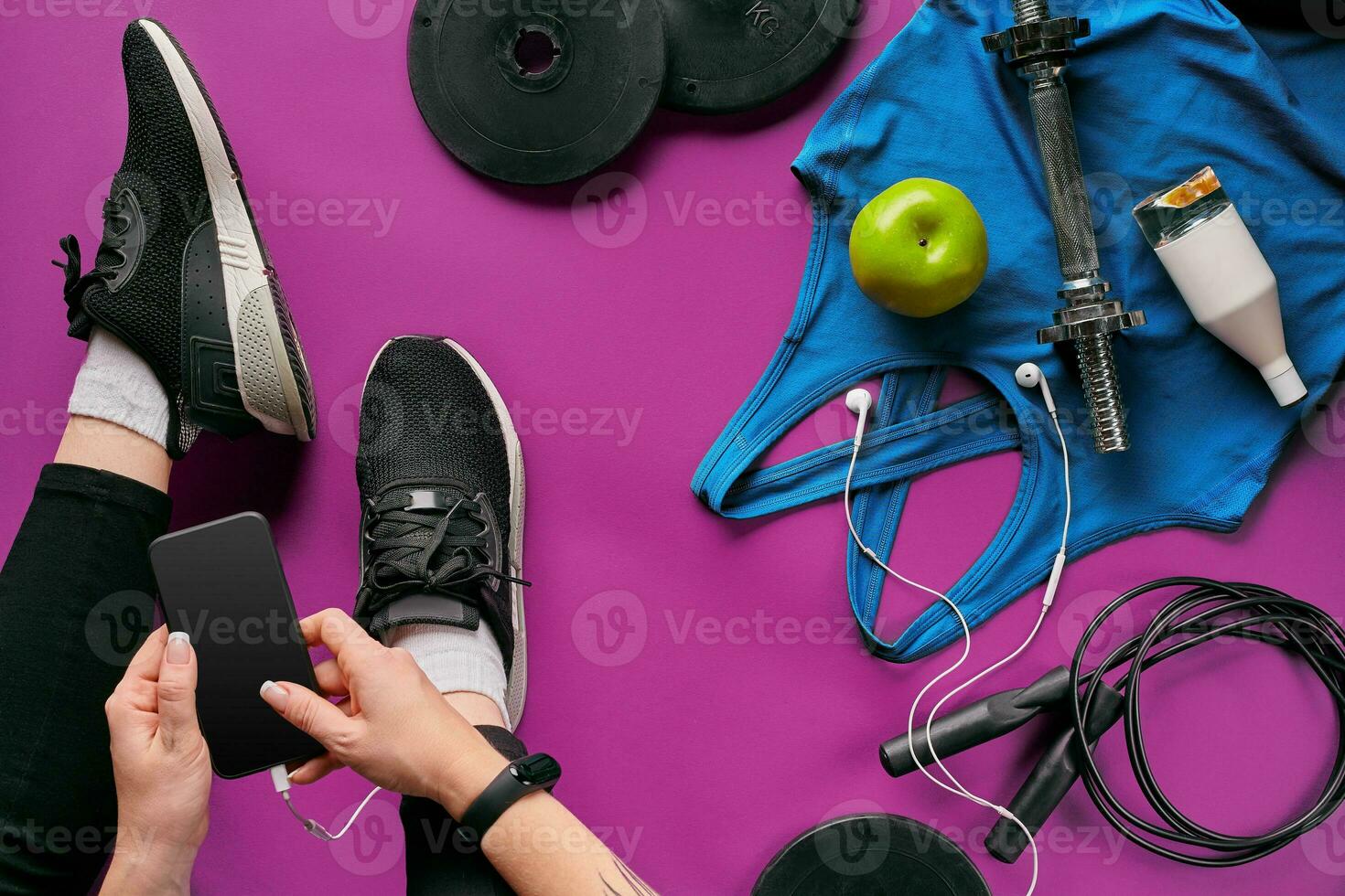 Young woman with mobile phone and sport equipment on color background flat lay top view. Fitness concept photo