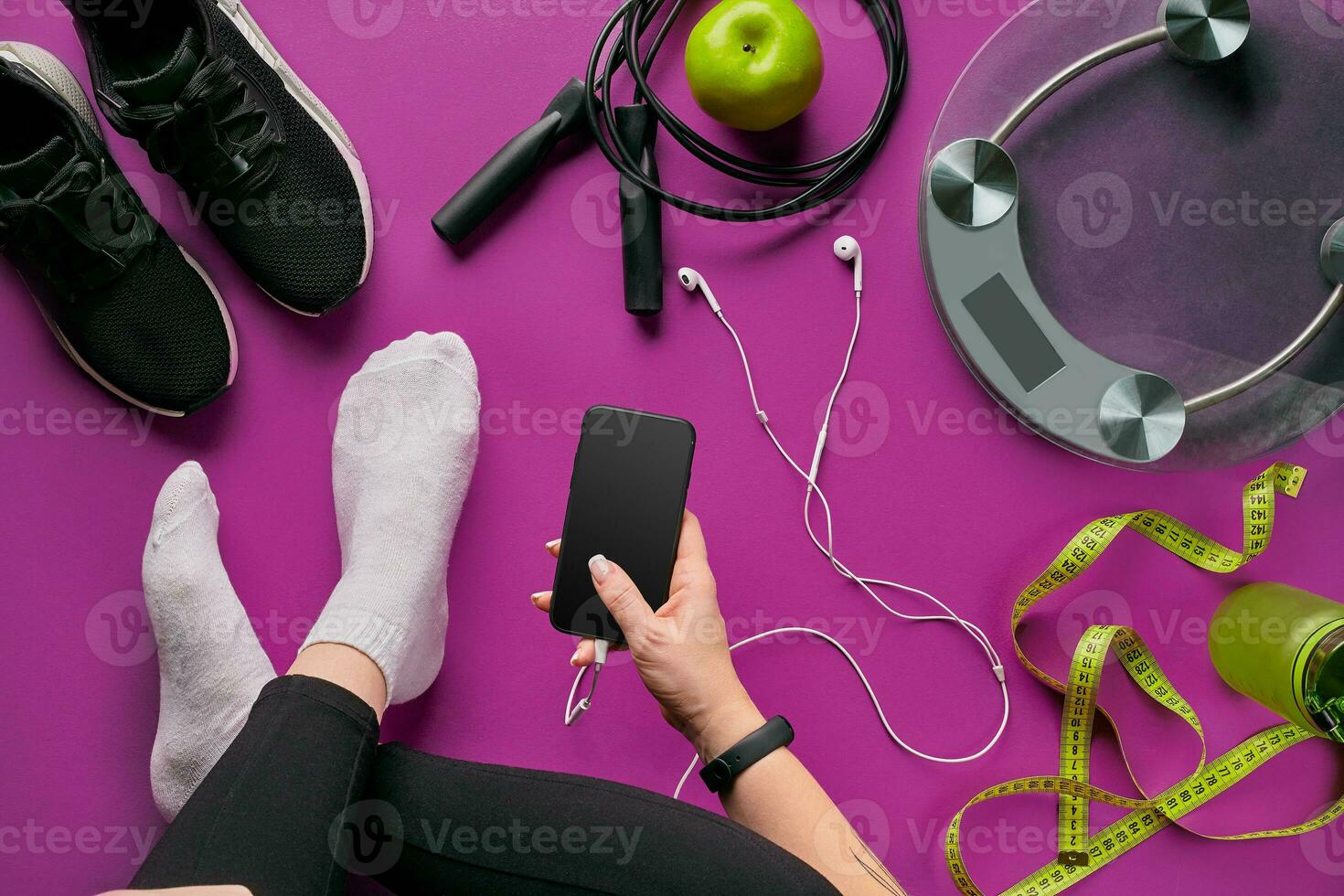 Young woman with mobile phone and sport equipment on color background flat lay top view. Fitness concept photo