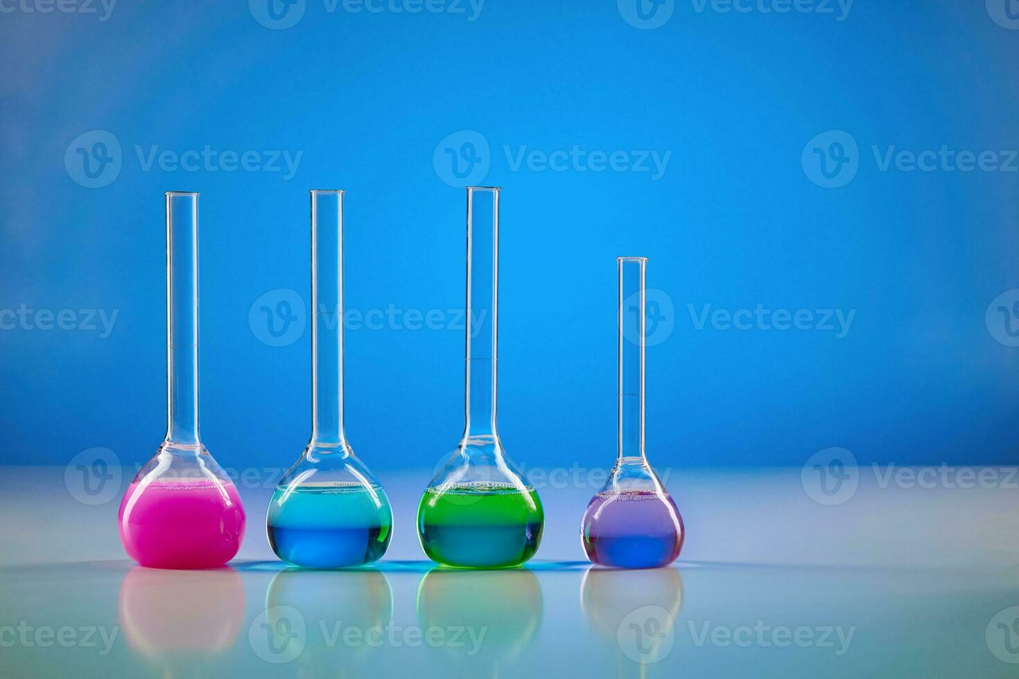 Four medical flasks with colorful chemical reagents for tests, blue background. Laboratory research of Coronavirus. Pandemic COVID-19. Close up photo