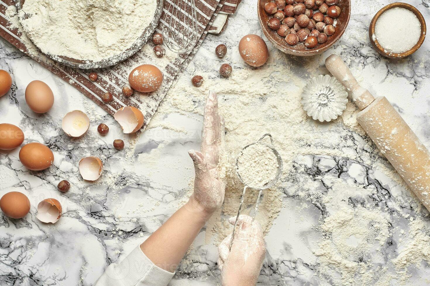 Close-up shot. Top view of a baker cook place, hands are working with a raw dough on the marble table background. photo