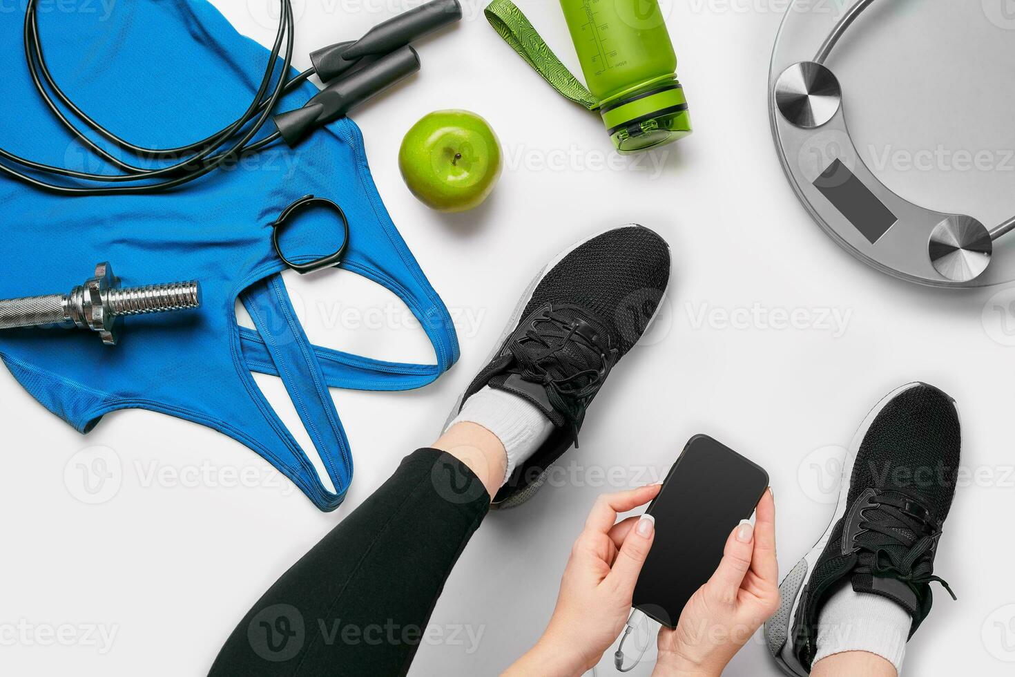 Young woman with mobile phone and sport equipment on white background flat lay top view. Fitness concept photo