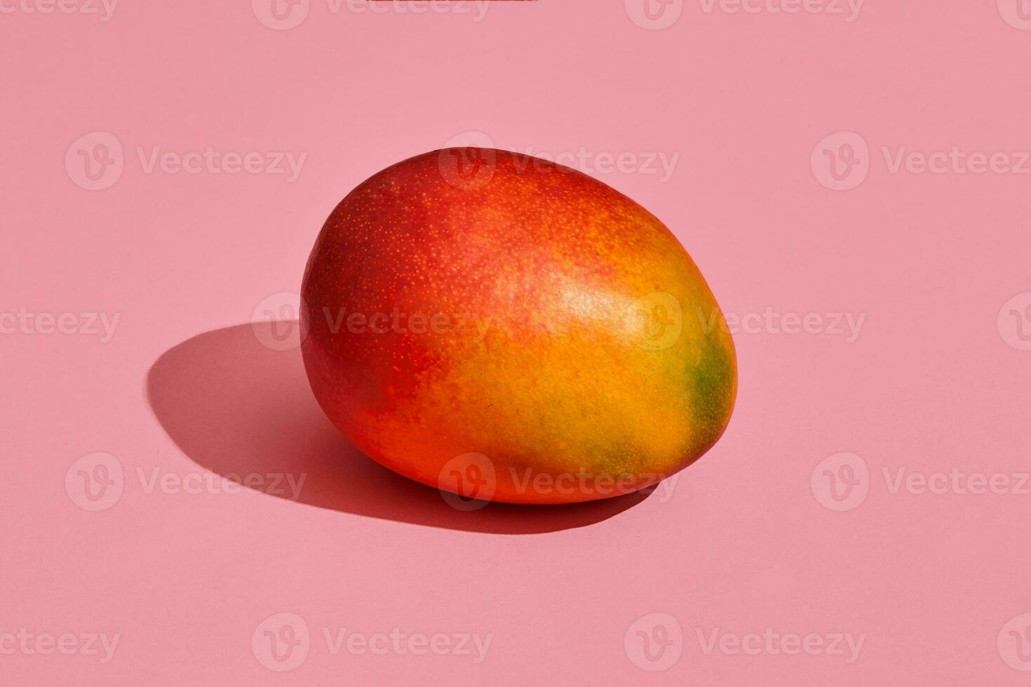 Colorful fruit pattern of fresh whole mango on coral pink background, top view photo
