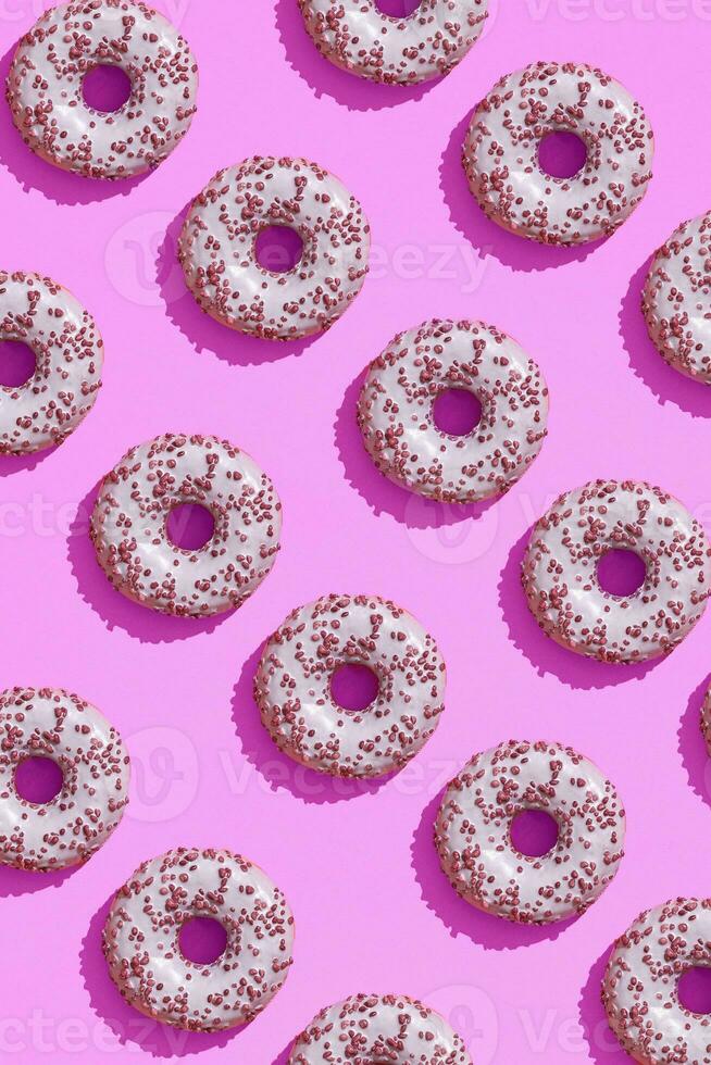 Food design with tasty pink glazed donut on purple lilac pastel background top view pattern photo