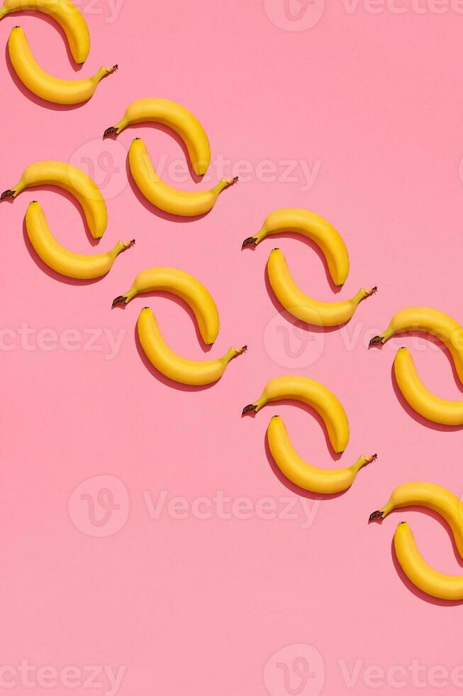 Pattern composition of a pair of bananas lying next to a pink background , top view photo