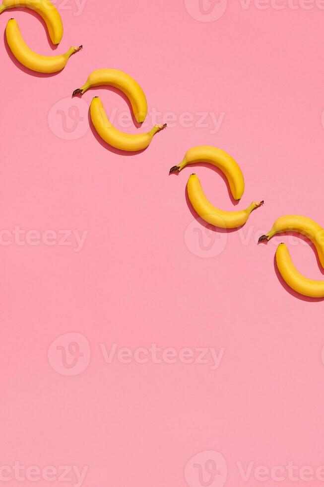 Pattern composition of a pair of bananas lying next to a pink background , top view photo