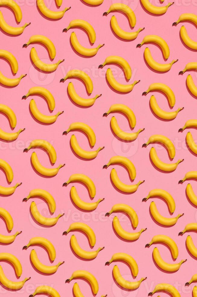 Pattern composition of a pair of bananas lying next to a pink background , top view photo