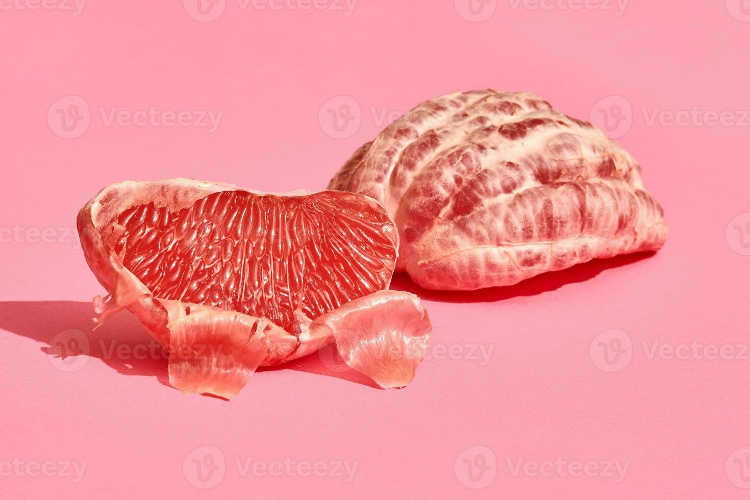 Close up high quality image of peeled slices of juicy grapefruit on a pink background photo