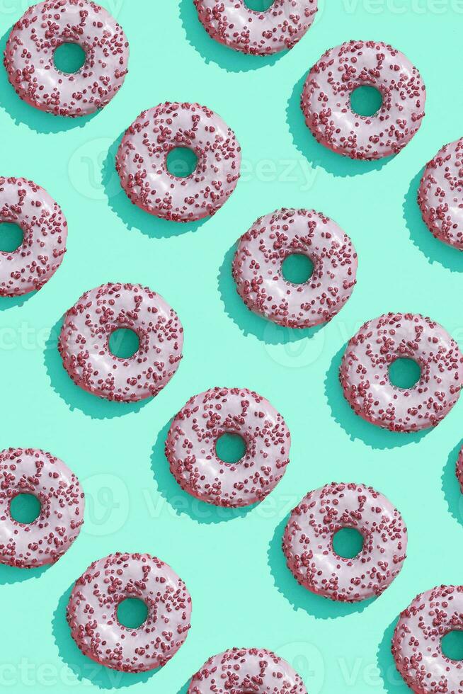 Food design with tasty pink glazed donut on aquamarine green-blue pastel background top view pattern photo