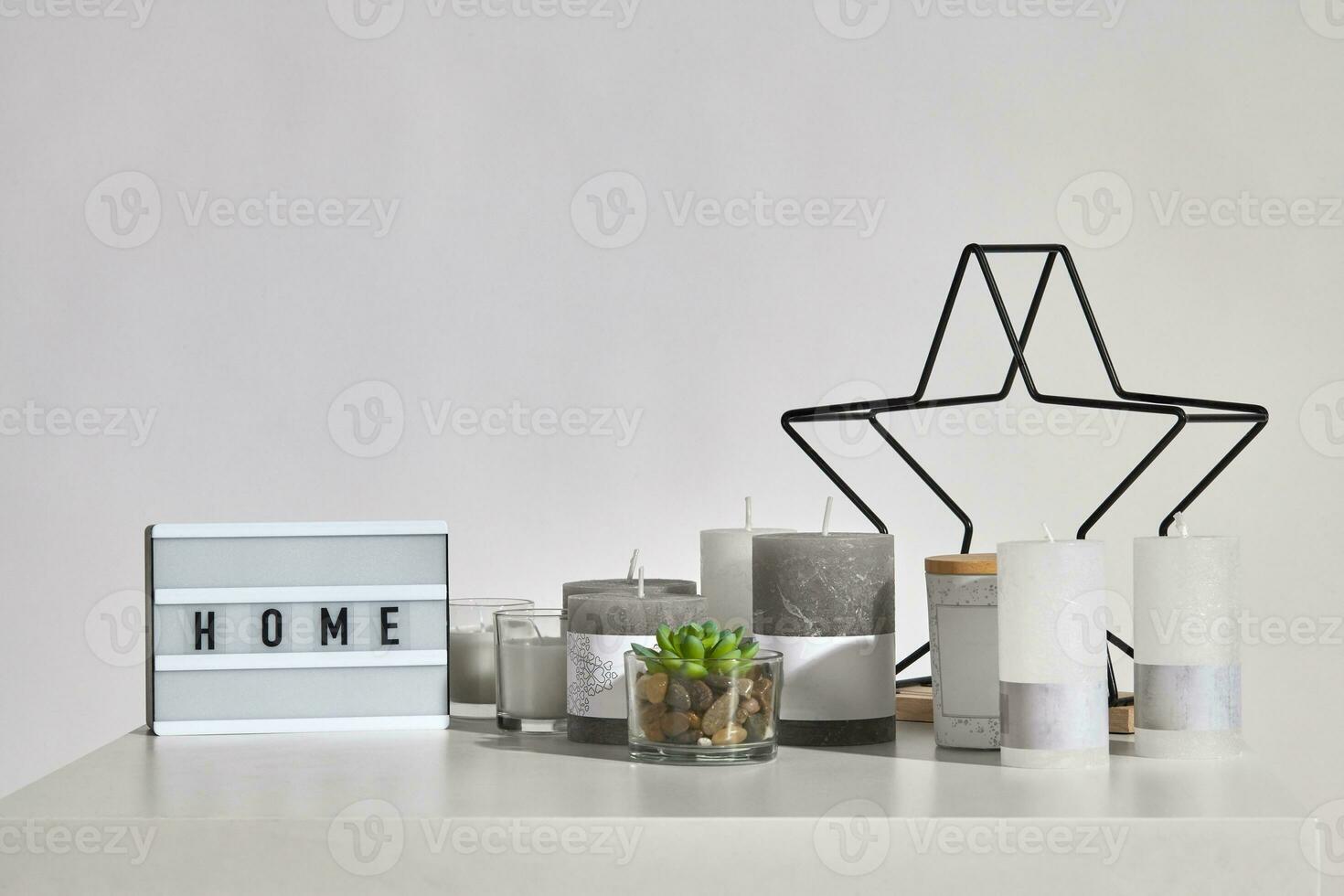 Table with green succulent, some candles, lamp with inscription home, black iron star, jar with wooden lid. Isolated on white background. Close up photo