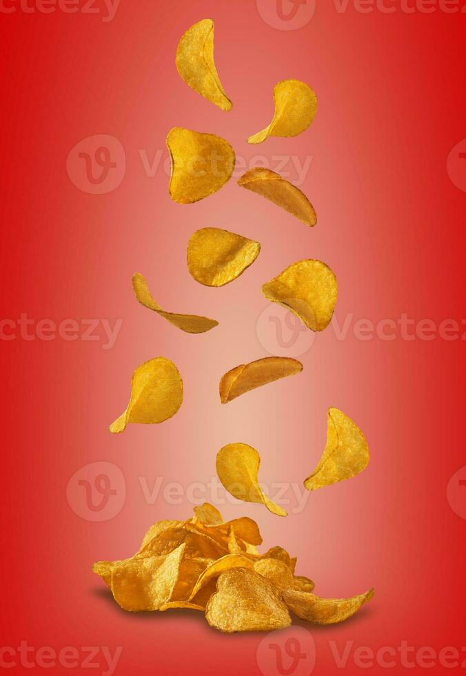 Potato crisps falling down against a red background with copy space for text or images. Crispy, palatable chips. Advertising. Close-up. photo