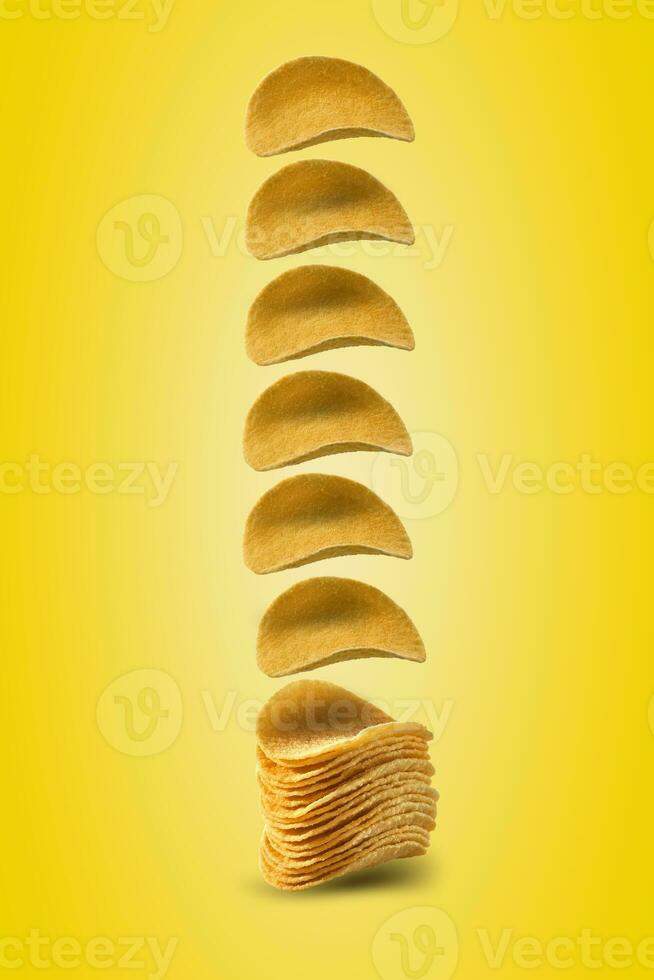 Potato crisps falling down against a yellow background with copy space for text or images. Crispy, palatable chips. Advertising. Close-up. photo