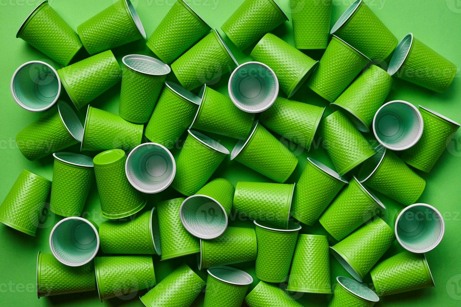 Green plastic disposable tableware on green background with copy space. The concept of picnic utensil. Top view. Selective focus. Close-up. photo