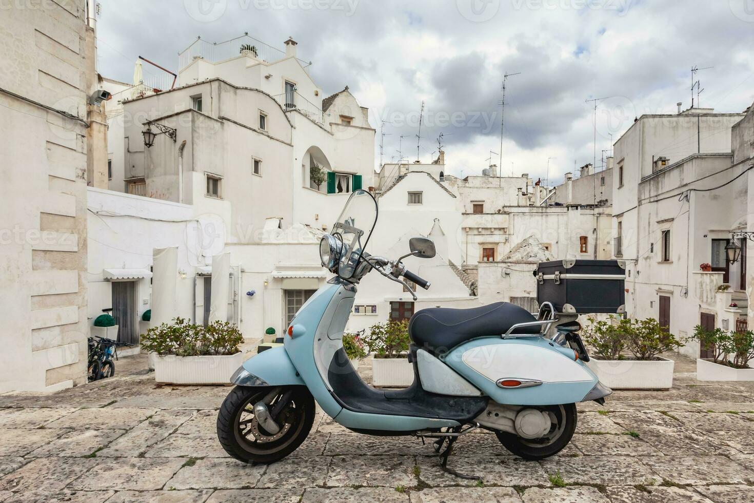 View of the old town of Martina Franca. Classic blue moped on the background of an anient buildings. photo