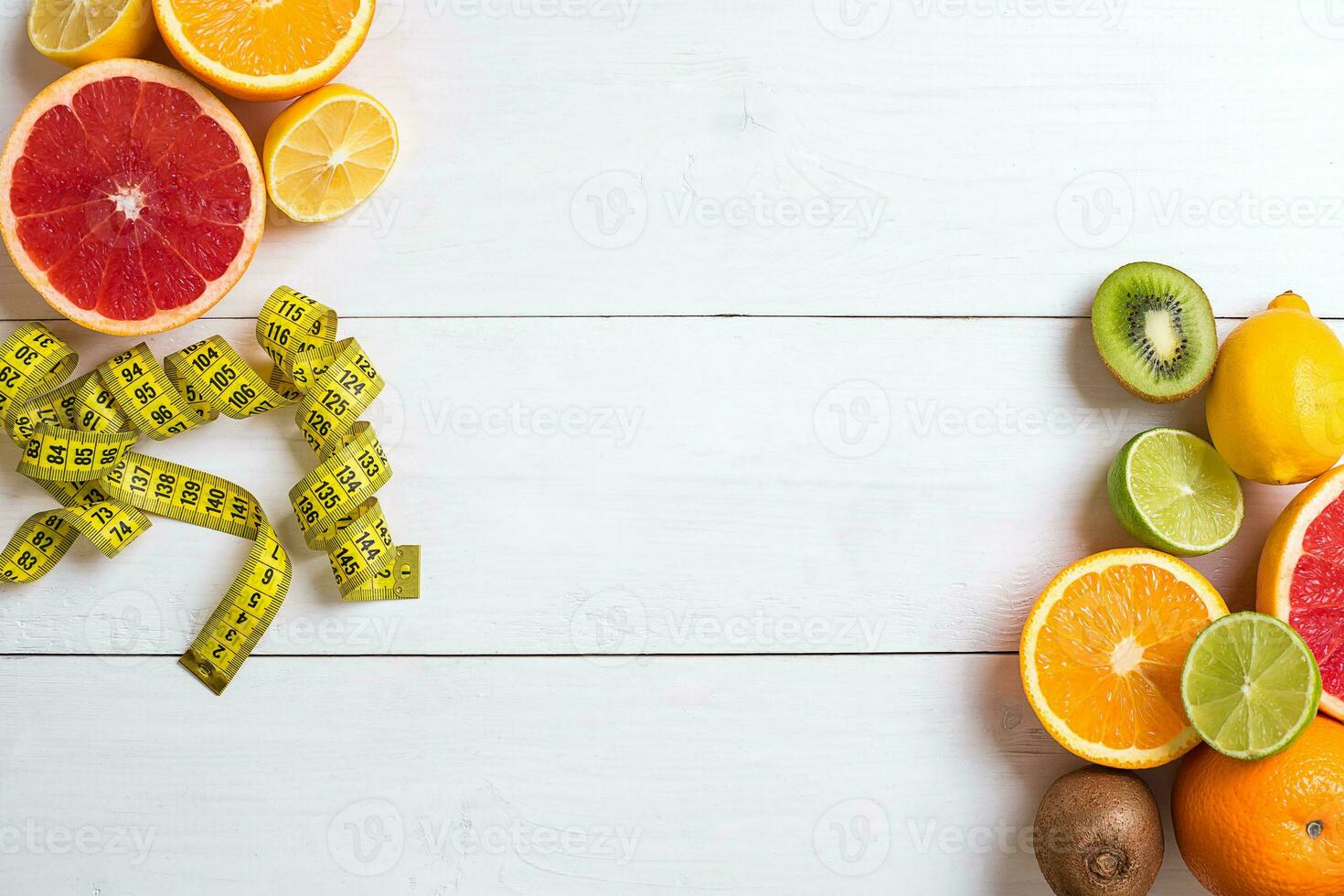 Fresh fruits with tape measure over white wooden background. Top view photo