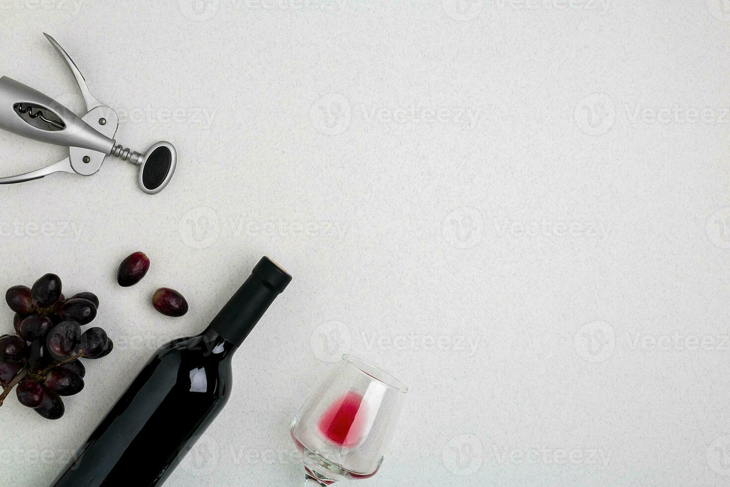 Overhead angled view of a large bottle of red wine, drinking glass on white background photo