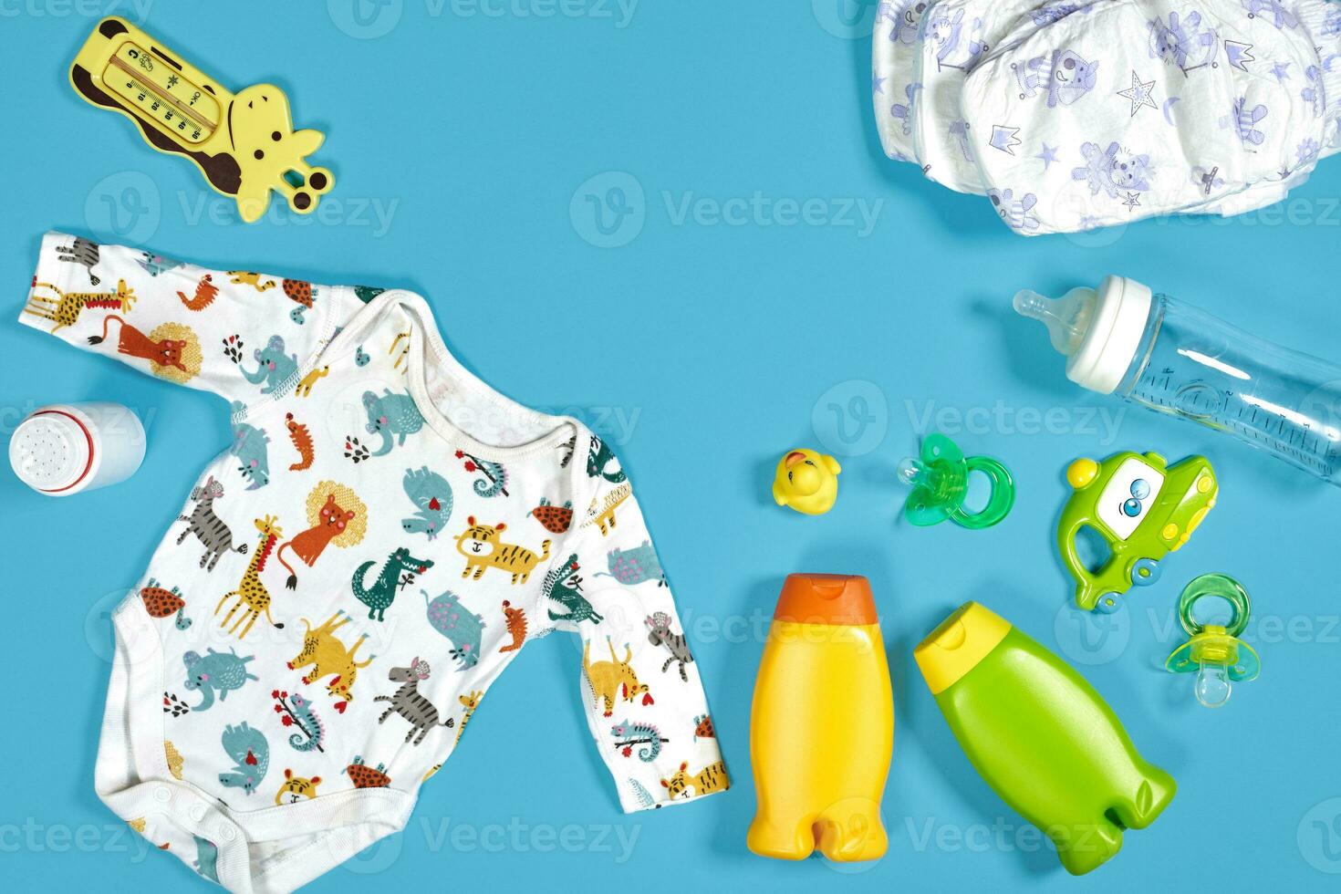 Baby care with bath set. Nipple, toy, clothes, shampoo on blue background top view mockup photo