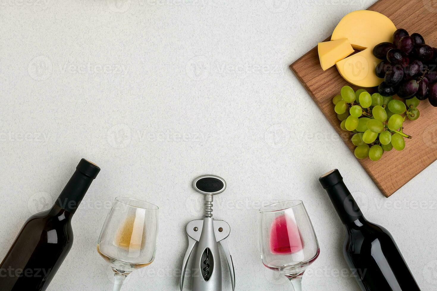 Two glasses of white and red wine, cheese and grapes. Top view photo