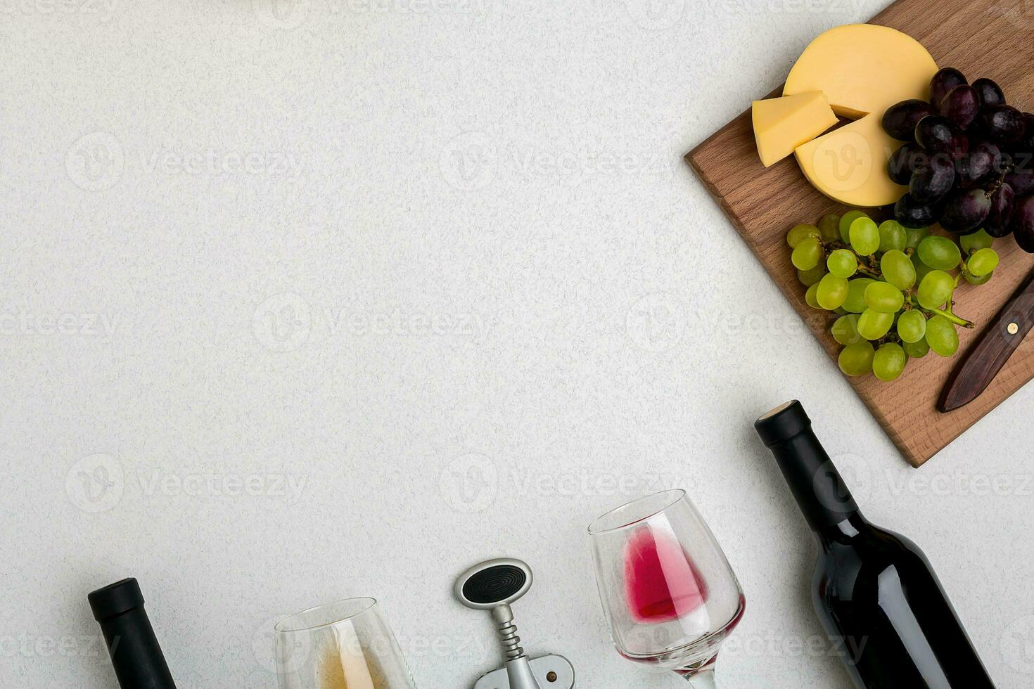Two glasses of white and red wine, cheese and grapes. Top view photo