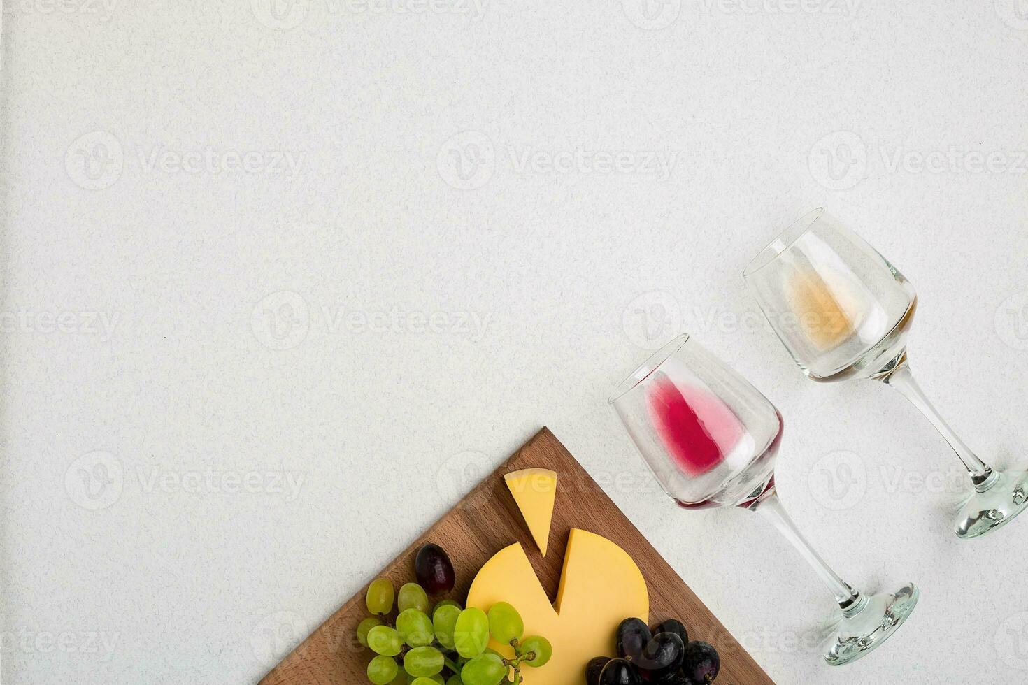 Two glasses of white and red wine, cheese and grapes. Top view photo