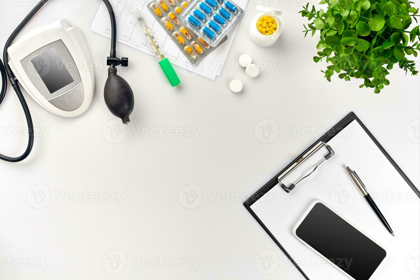 Top view of doctor's desk table, blank paper on clipboard with pen, electronic manometer to measure the blood pressure. photo