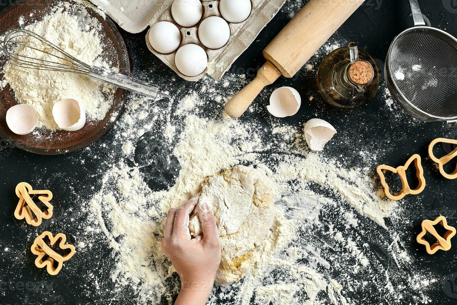 Woman's hands knead dough on table with flour, eggs and ingredients. Top view. photo