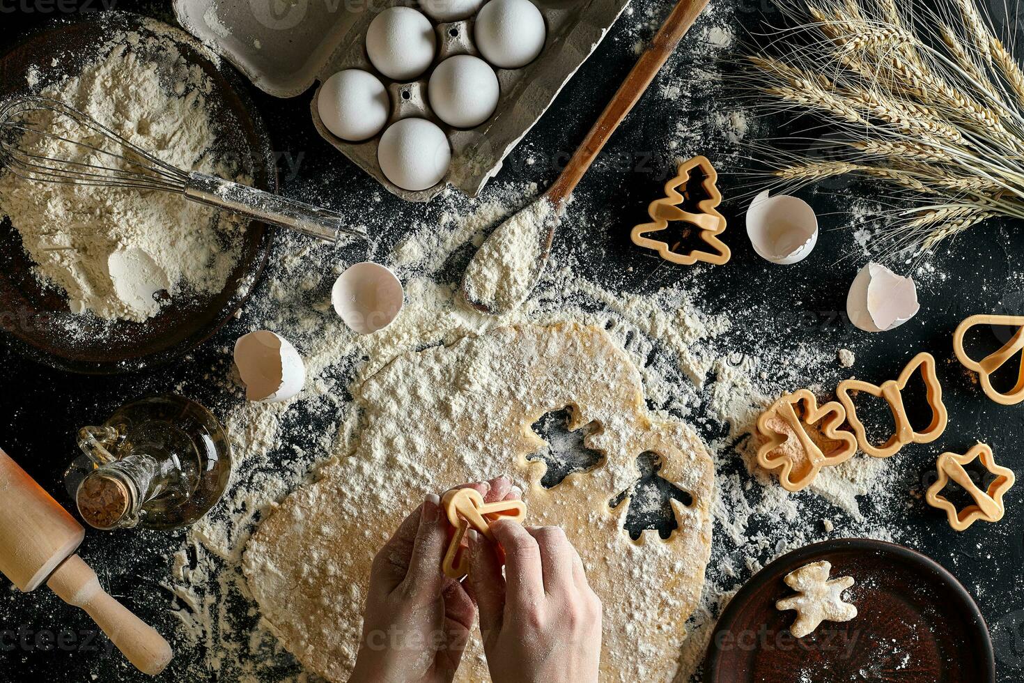 de cerca de un mujer mano con un masa. el mujer es corte un Galleta con un Galleta cortador en el forma de un pequeño humano. ver desde arriba. foto