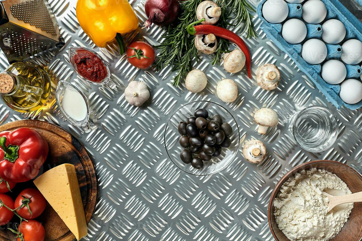 Food ingredients and spices for cooking pizza. Mushrooms, tomatoes, cheese, onion, oil, pepper, salt, egg, grater on metal background. Copy space. Top view photo