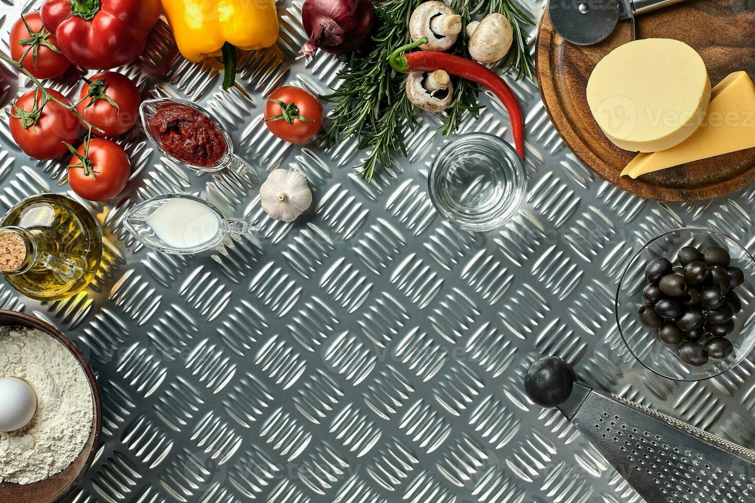 Food ingredients and spices for cooking pizza. Mushrooms, tomatoes, cheese, onion, oil, pepper, salt, egg, grater on metal background. Copy space. Top view photo