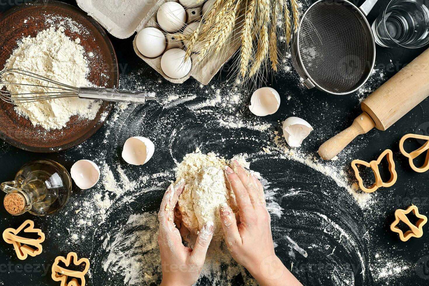 Woman's hands knead dough on table with flour, eggs and ingredients. Top view. photo