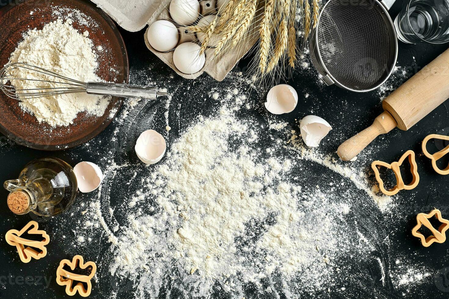 Cooking dough for cookies, butter, eggs, cooking equipment, flour on a black table. Top view with copy space, mockup for menu, recipe or culinary classes. Baking background. photo