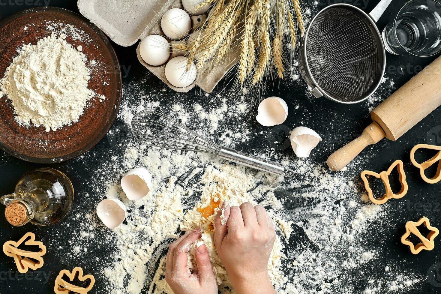 Woman's hands knead dough on table with flour, eggs and ingredients. Top view. photo