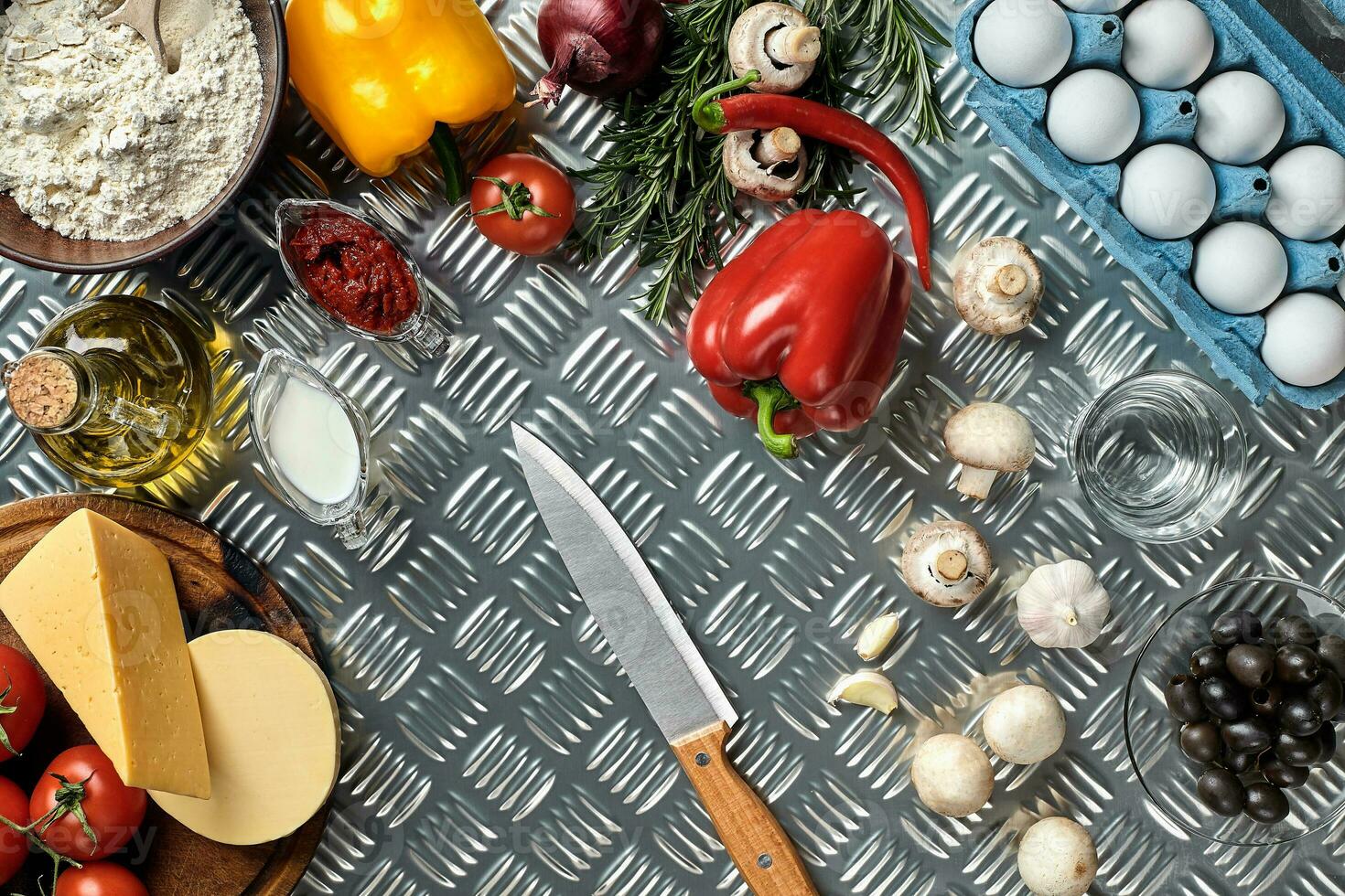 Food ingredients and spices for cooking pizza. Mushrooms, tomatoes, cheese, onion, oil, pepper, salt, egg, grater on metal background. Copy space. Top view photo