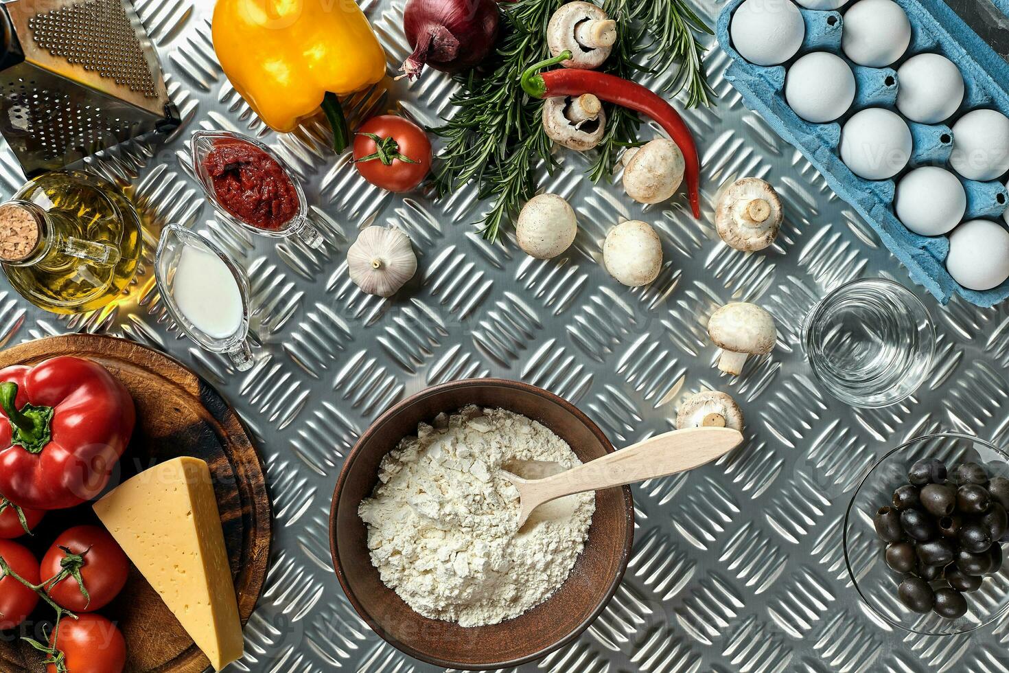 Food ingredients and spices for cooking pizza. Mushrooms, tomatoes, cheese, onion, oil, pepper, salt, egg, grater on metal background. Copy space. Top view photo