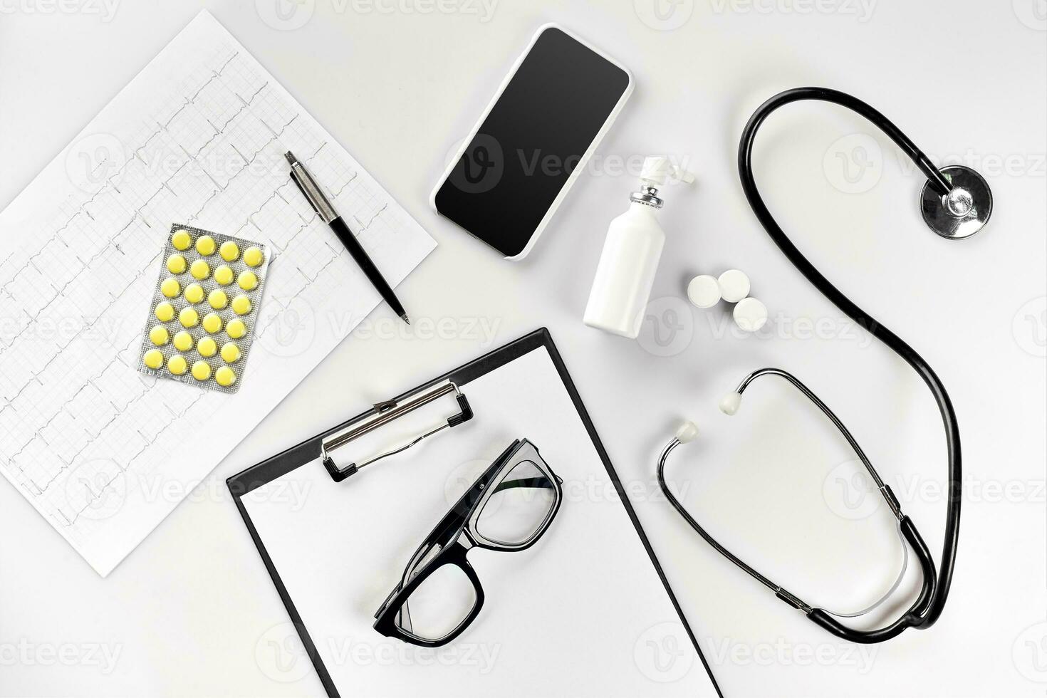 Doctor's office desk with medical documents, charts, eyeglasses and stethoscope. Top view. Copy space photo