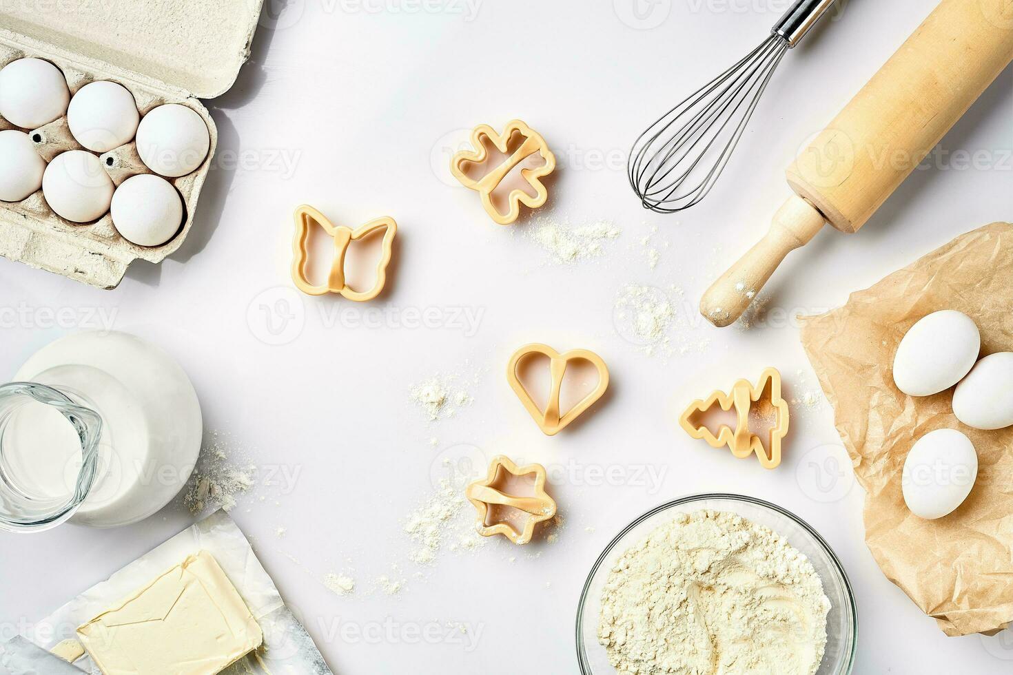 Objects and ingredients for baking, plastic molds for cookies on a white background. Flour, eggs, rolling pin, whisk, milk, butter, cream. Top view, space for text photo